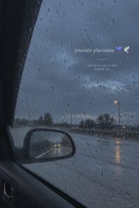 Femme conductrice souriante au volant par temps de pluie sur une route mouillée.